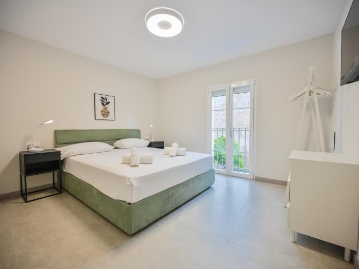 Double bed in bedroom with air conditioner and flatscreen TV