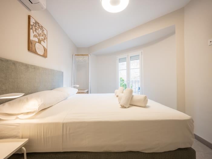 Flatscreen TV, airconditioner and nightstands with lamps in bedroom