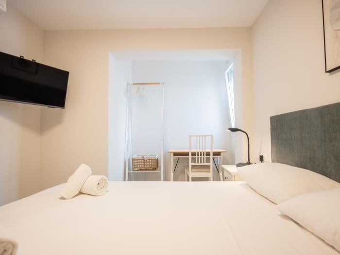 Working area in bedroom with double bed, airconditioner, nightstands with lamps