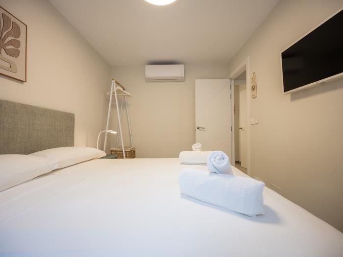 Double bed in bedroom with flatscreen TV, airconditioners, nightstands with lamps